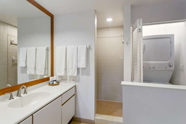 bathroom featuring tiled shower, vanity, and stacked washer / drying machine