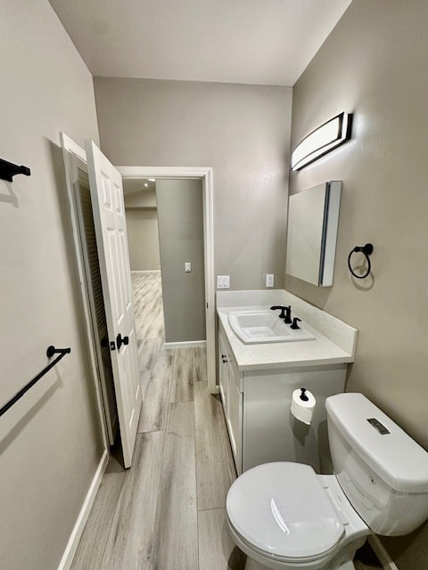 bathroom featuring toilet, wood finished floors, vanity, and baseboards