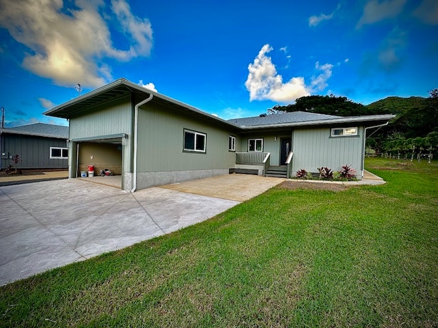 rear view of house featuring a garage, driveway, and a lawn