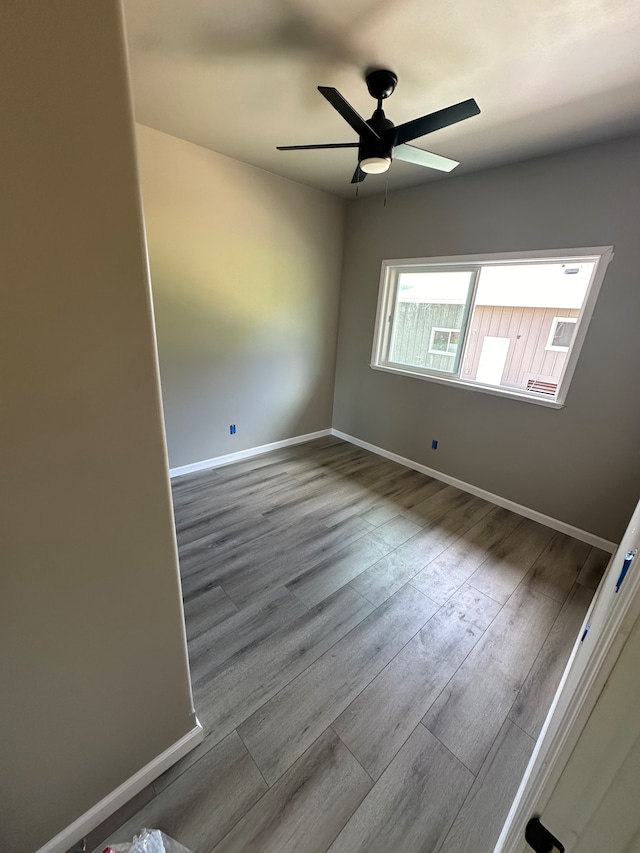 unfurnished room with a ceiling fan, light wood-style flooring, and baseboards