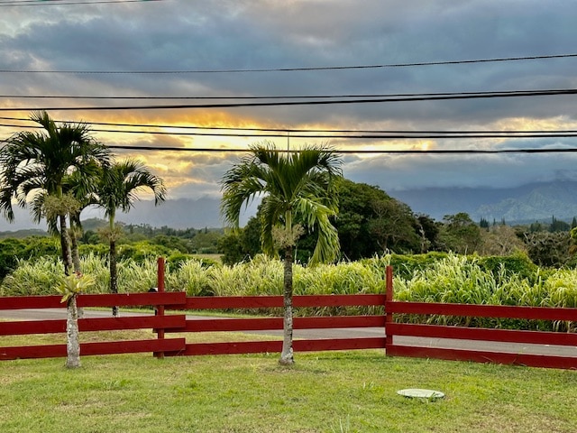 gate at dusk featuring fence and a lawn