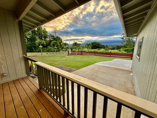 deck at dusk featuring a yard and fence