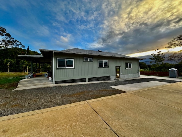 back house at dusk featuring a carport