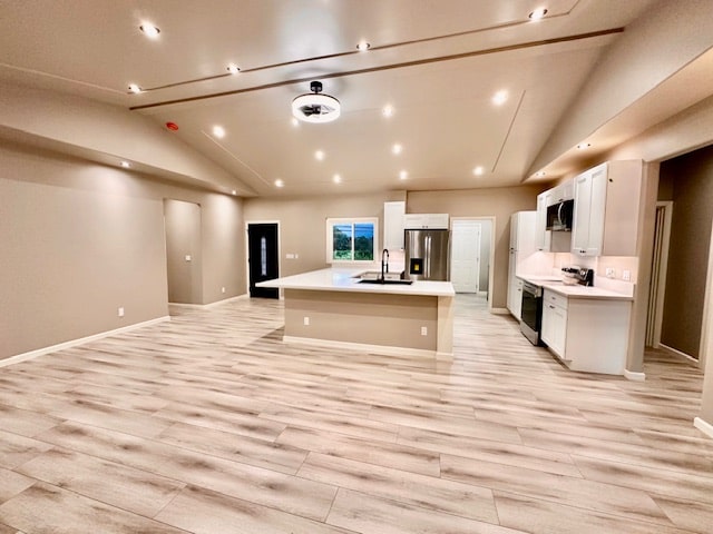 kitchen featuring a kitchen island with sink, white cabinetry, light hardwood / wood-style flooring, stainless steel appliances, and vaulted ceiling