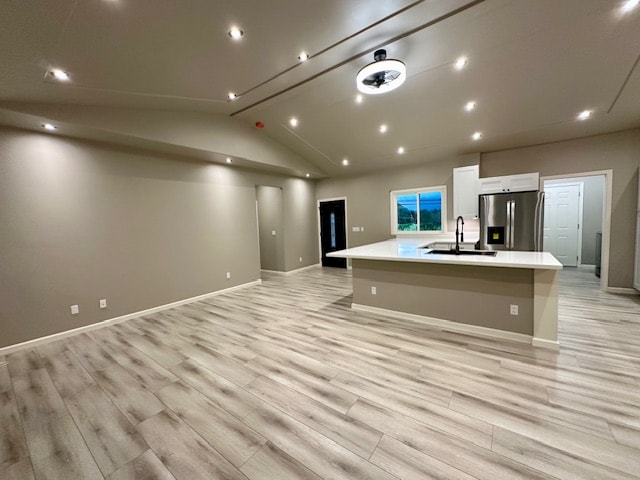 kitchen with stainless steel refrigerator with ice dispenser, a large island with sink, white cabinetry, and light hardwood / wood-style flooring