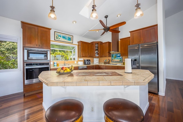 kitchen with appliances with stainless steel finishes, lofted ceiling with skylight, a breakfast bar area, and brown cabinets
