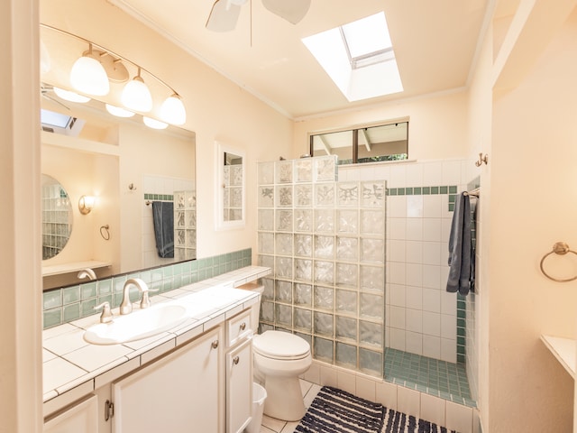 bathroom with toilet, tile patterned floors, vanity, a tile shower, and a skylight