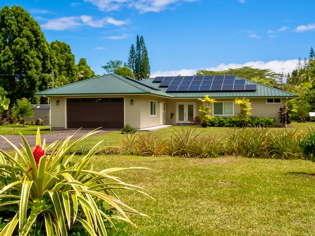 ranch-style home with a garage, solar panels, and a front yard