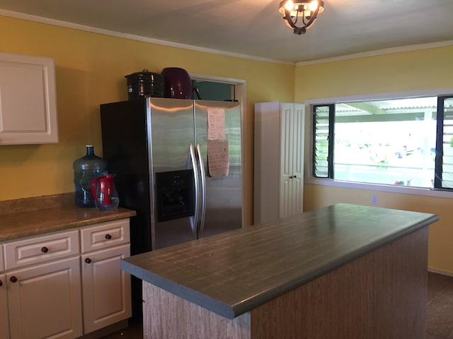 kitchen featuring white cabinets, a kitchen island, ornamental molding, and stainless steel refrigerator with ice dispenser