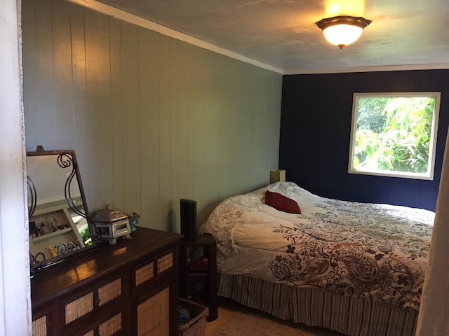 bedroom featuring wood-type flooring, ornamental molding, and wooden walls