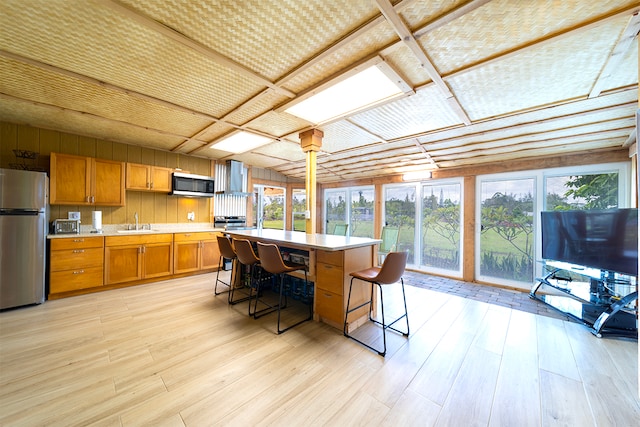 kitchen featuring a breakfast bar, pendant lighting, stainless steel appliances, light hardwood / wood-style flooring, and sink