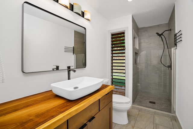 bathroom featuring vanity, toilet, and tiled shower