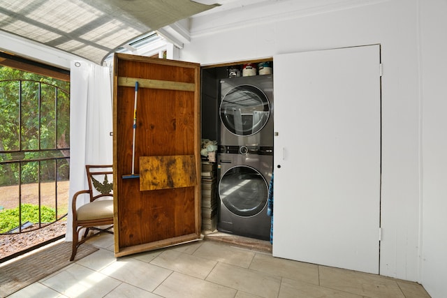 laundry room featuring a wealth of natural light, light tile patterned floors, and stacked washer and dryer