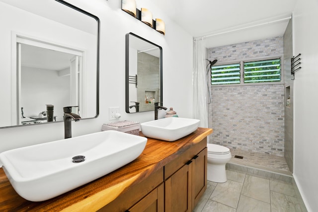 bathroom featuring tiled shower, toilet, and vanity