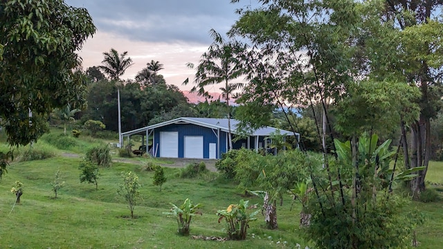 property exterior at dusk with a garage and a lawn