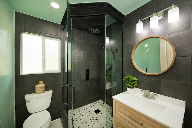 bathroom featuring toilet, walk in shower, vanity, and tile walls