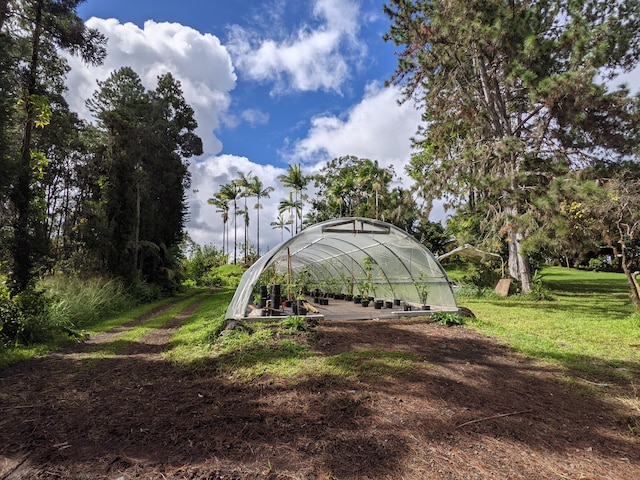 view of grassy yard with a greenhouse and an outdoor structure