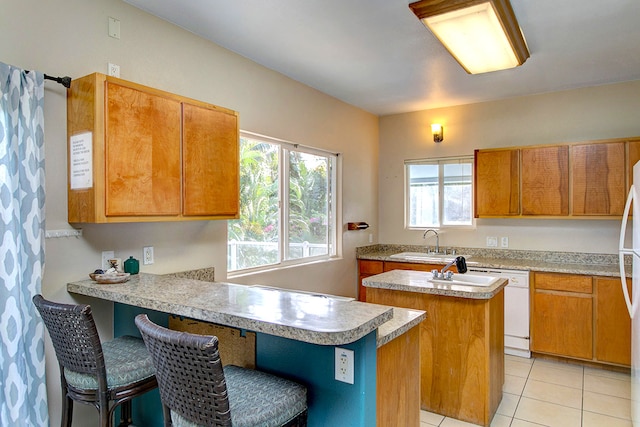 kitchen with light tile patterned floors, a kitchen island, sink, and a breakfast bar