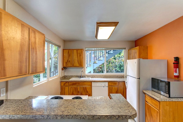 kitchen with white appliances, kitchen peninsula, and sink