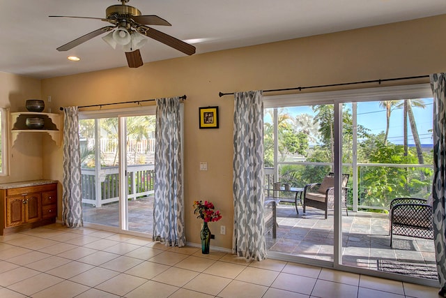 doorway featuring a healthy amount of sunlight, ceiling fan, and light tile patterned floors