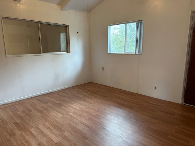 empty room featuring lofted ceiling and hardwood / wood-style flooring