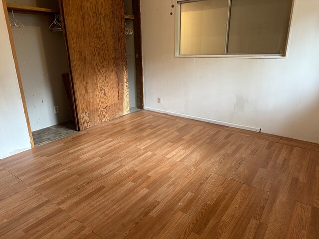 unfurnished bedroom featuring wood-type flooring and a closet