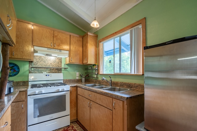 kitchen featuring white range with gas stovetop, stainless steel fridge, decorative light fixtures, sink, and vaulted ceiling with beams