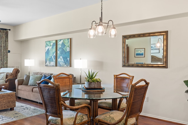 dining area featuring dark wood-type flooring and an inviting chandelier