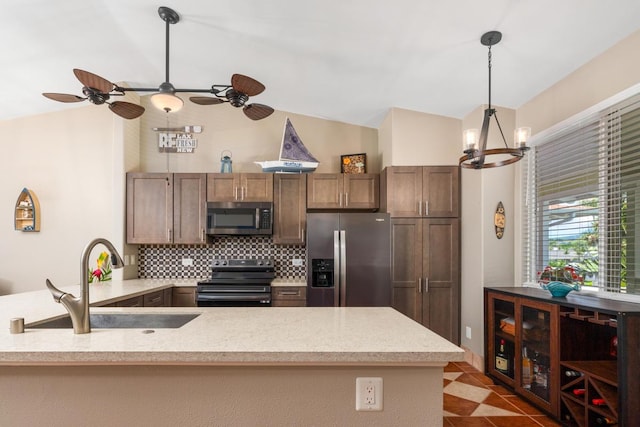 kitchen with ceiling fan with notable chandelier, pendant lighting, stainless steel appliances, sink, and lofted ceiling