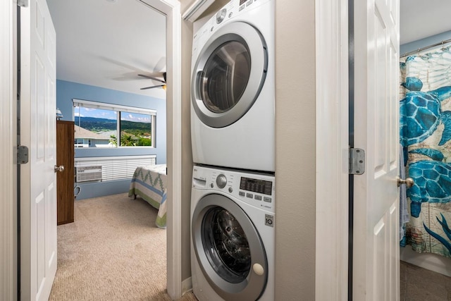 laundry area featuring stacked washer and clothes dryer, ceiling fan, and light carpet