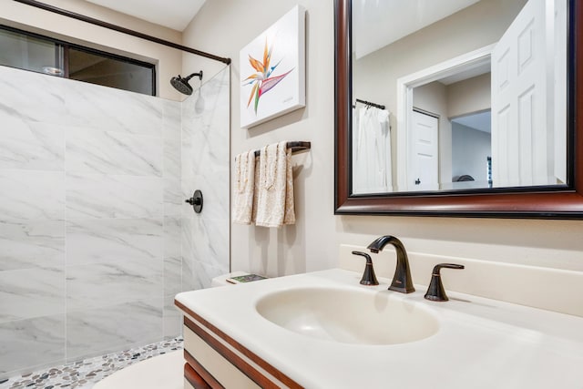 bathroom with toilet, vanity, and a tile shower