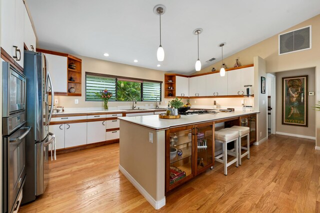 kitchen featuring white cabinetry, lofted ceiling, decorative light fixtures, and light wood-type flooring