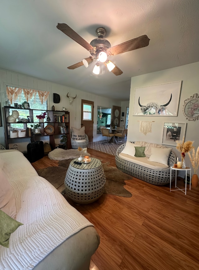 living room featuring a textured ceiling, wood-type flooring, and ceiling fan