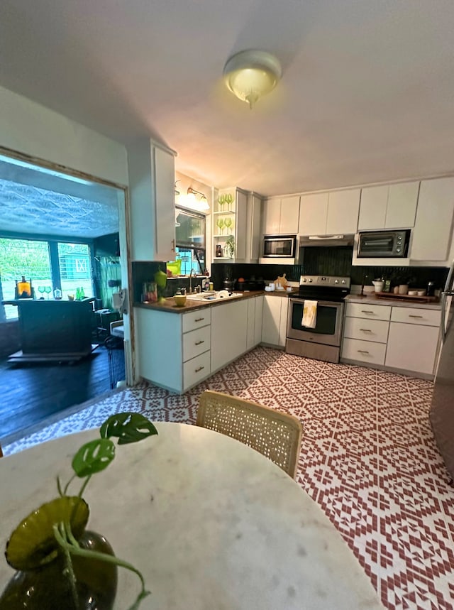 kitchen with sink, white cabinets, decorative backsplash, and stainless steel appliances