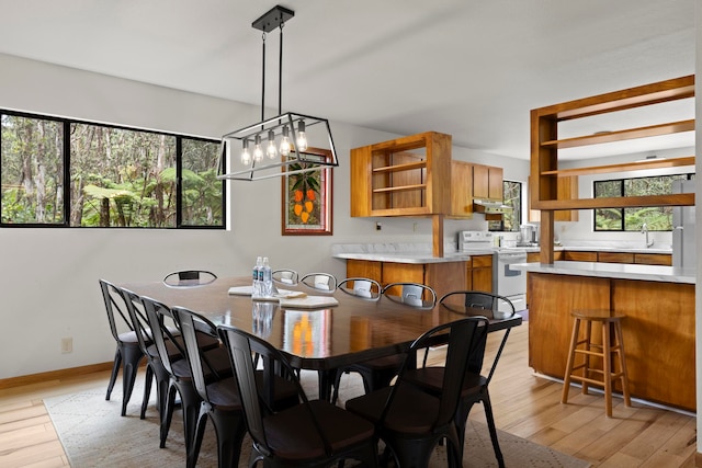 dining room featuring an inviting chandelier, light hardwood / wood-style flooring, and sink