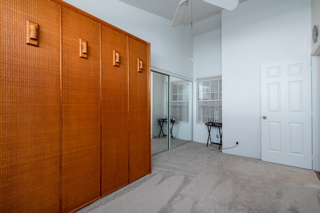 interior space featuring a high ceiling, light colored carpet, and ceiling fan