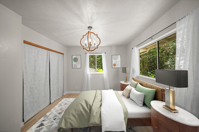 bedroom with a notable chandelier, light wood-type flooring, and a textured ceiling