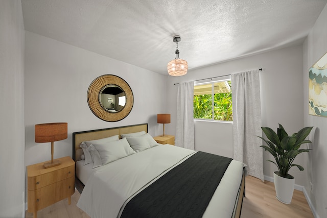 bedroom with a textured ceiling and light wood-type flooring