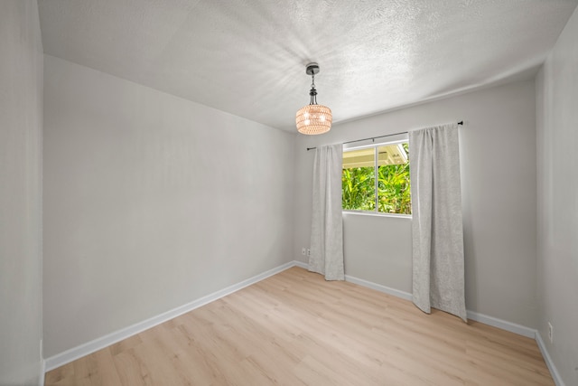 unfurnished room featuring light hardwood / wood-style flooring and a textured ceiling