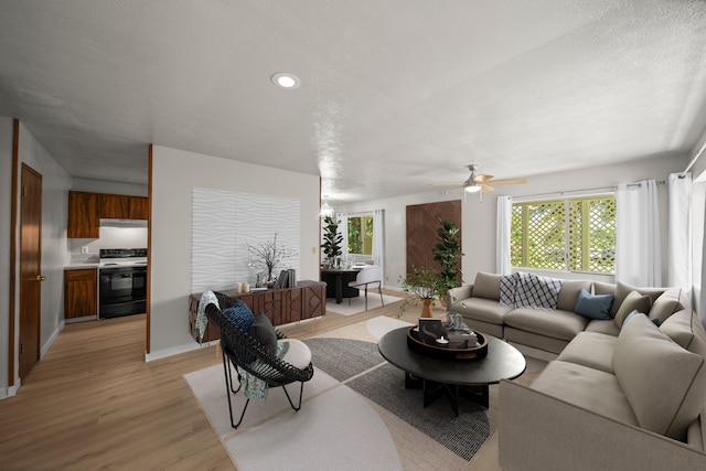 living room featuring light hardwood / wood-style flooring, ceiling fan, and a textured ceiling