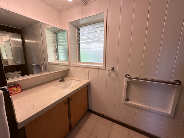 bathroom with wood walls, vanity, a textured ceiling, tile patterned flooring, and toilet