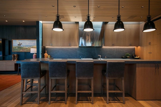 kitchen featuring wood ceiling, a kitchen bar, decorative backsplash, and light hardwood / wood-style flooring