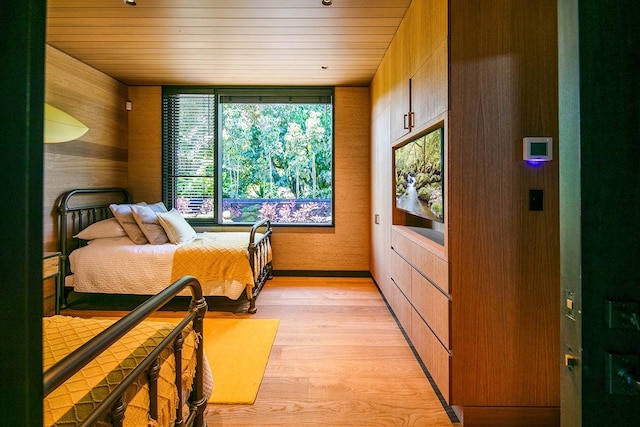 bedroom with wooden walls, wooden ceiling, and light hardwood / wood-style flooring