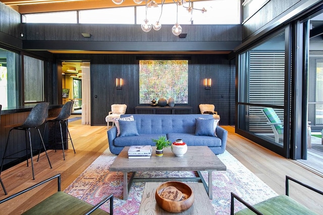 living room with high vaulted ceiling, light wood-type flooring, and a chandelier