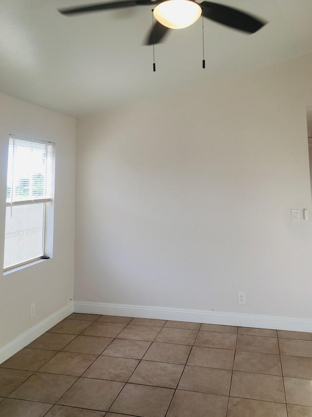 empty room with ceiling fan and light tile patterned floors