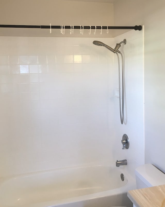 bathroom featuring tiled shower / bath and toilet