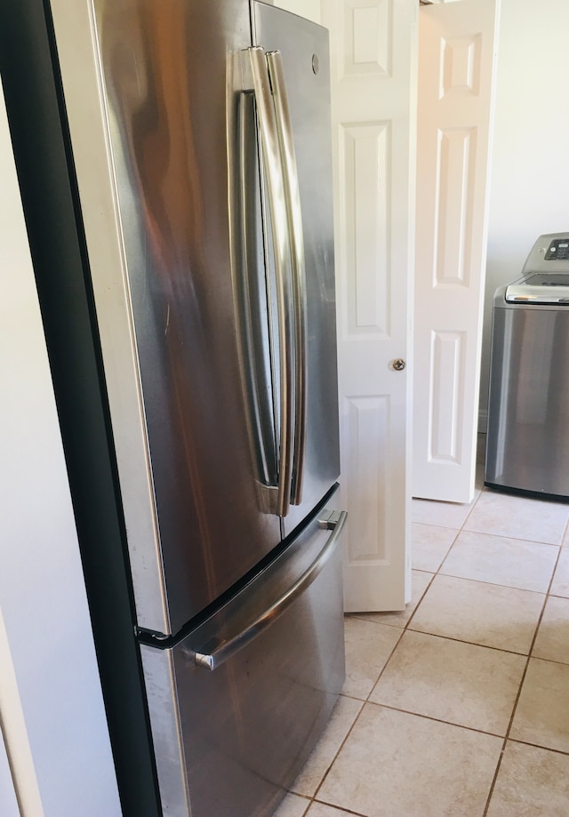 interior space with light tile patterned floors, washer / dryer, and stainless steel fridge