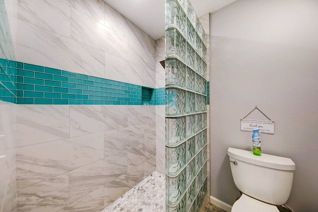 bathroom featuring tiled shower and toilet