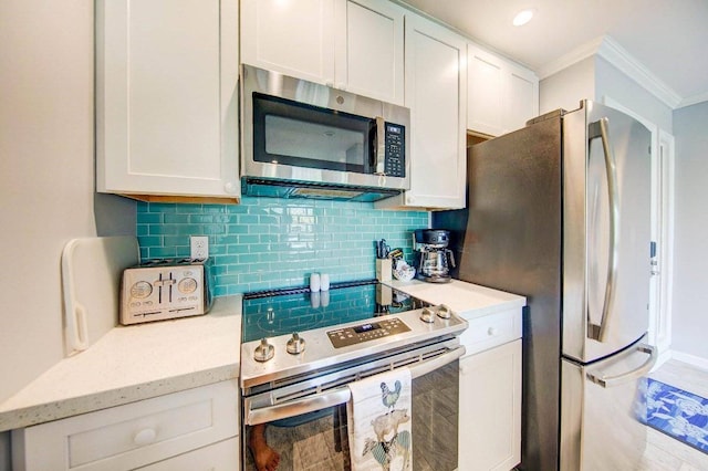 kitchen with crown molding, appliances with stainless steel finishes, white cabinetry, and decorative backsplash