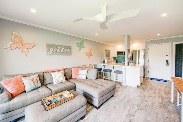 living room with ornamental molding, light hardwood / wood-style flooring, and ceiling fan